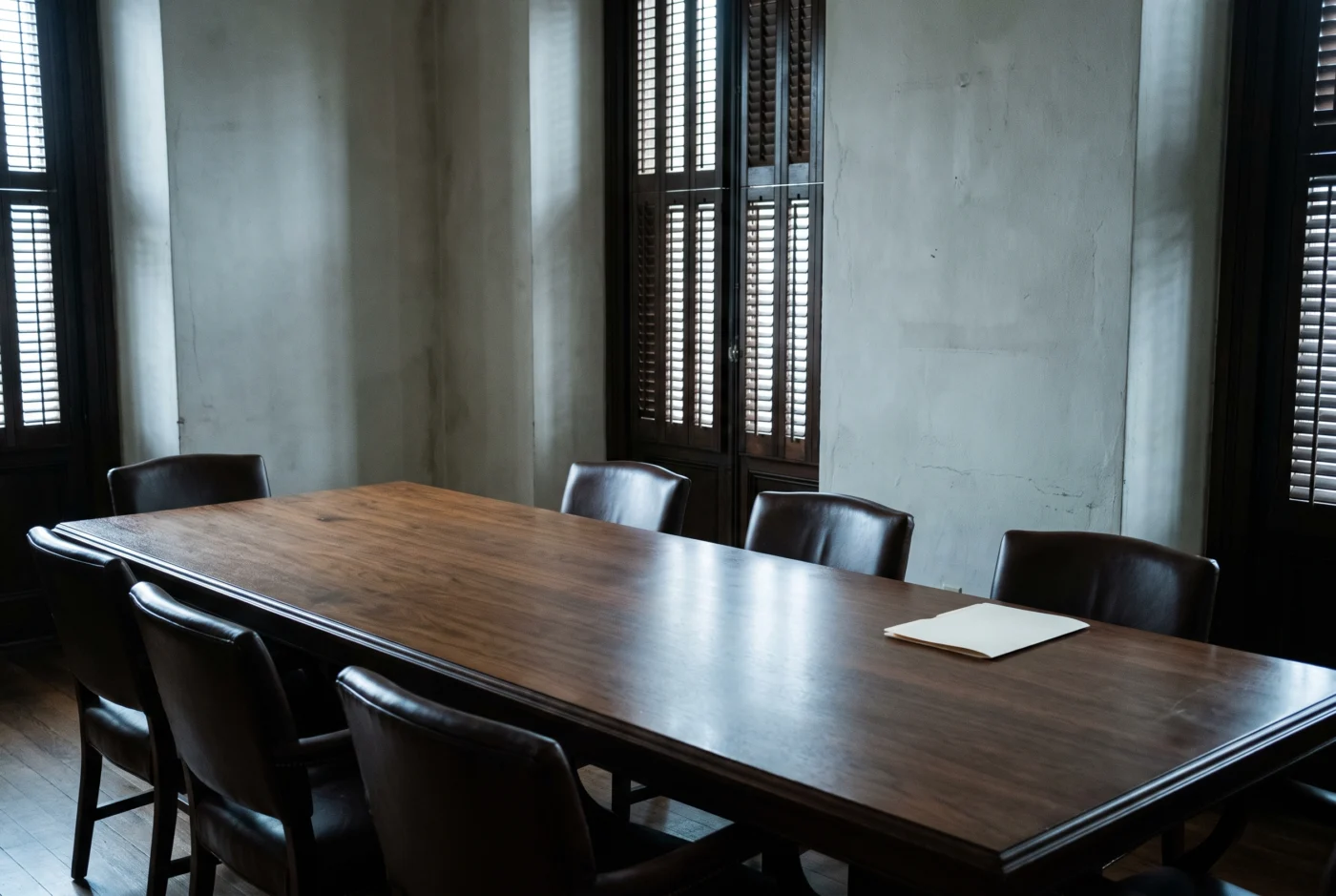Sala de reuniones del despacho con mesa de nogal y luz de contraventana